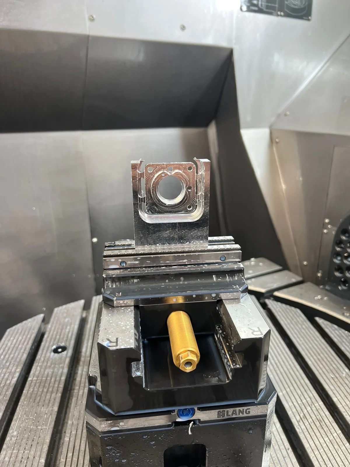 Machined part clamped in a vise on the machining centre