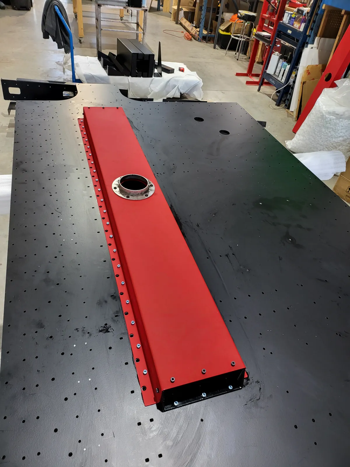 Red machined bar mounted on a black perforated plate